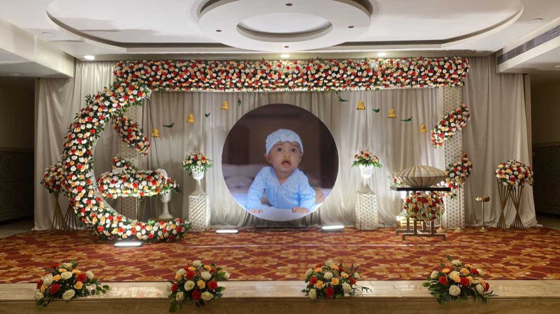Naming ceremony stage in Hyderabad with a floral cradle setup and name backdrop