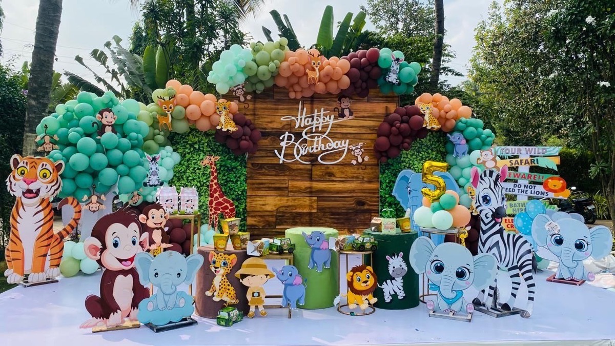 Jungle safari themed birthday decoration in Hyderabad with pastel balloon arch, animal cutouts and a wooden backdrop