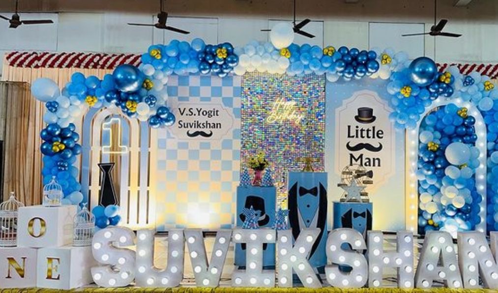 Blue and gold first birthday decoration in Hyderabad with a shimmer wall, balloon arch and light-up name letters