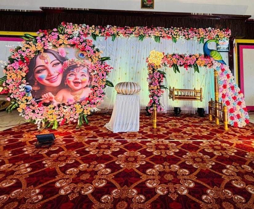 Naming ceremony barasala decoration in Hyderabad with a floral cradle, decorated swing and a Krishna themed round backdrop