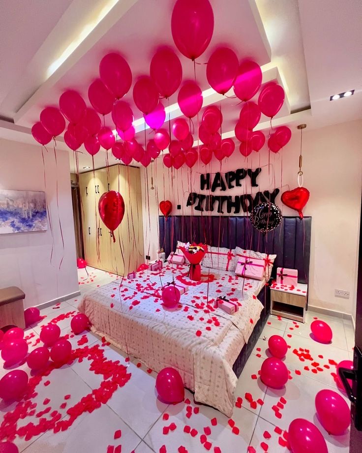 Romantic anniversary room surprise in Hyderabad with ceiling balloons and rose petals across the bed